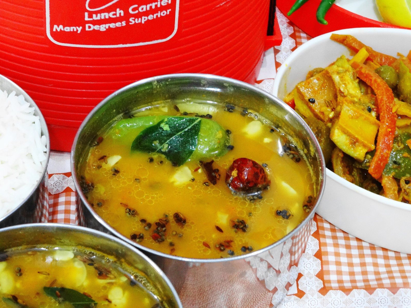 Dal and vegetable curries in steel containers beside rice